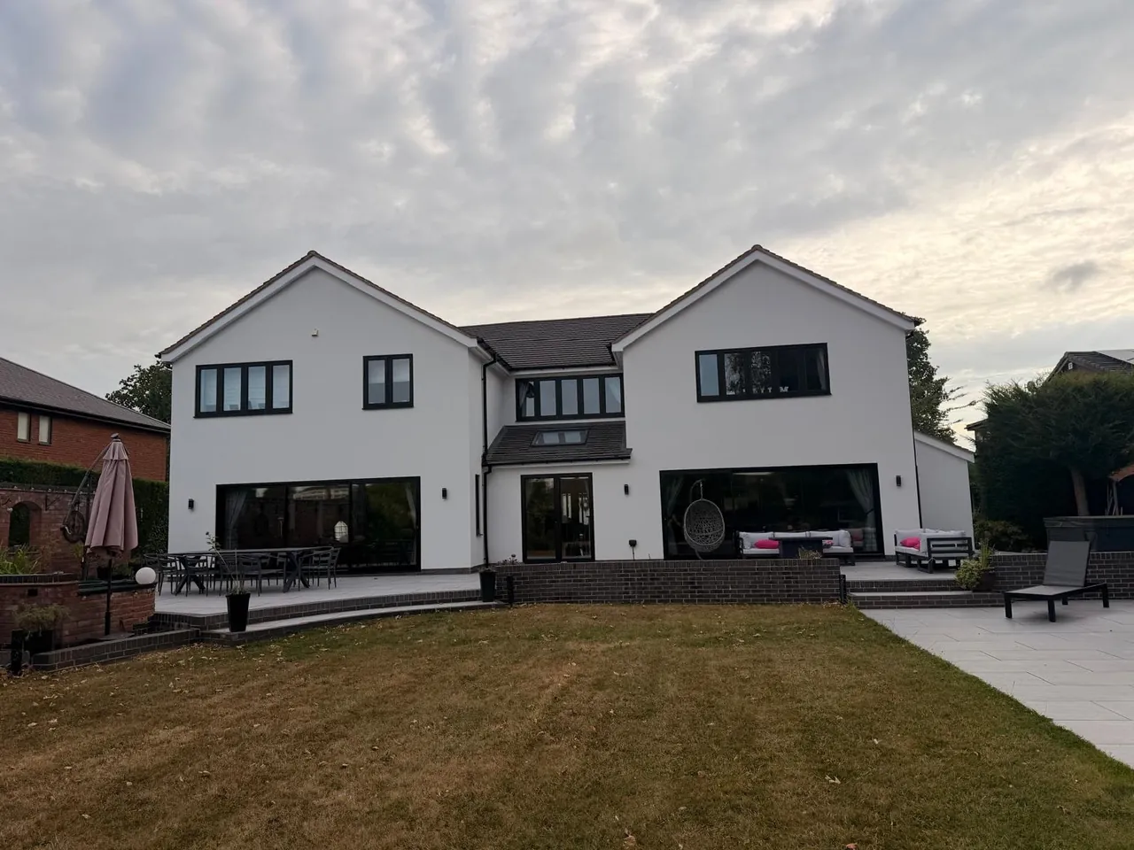 Large two-storey rear extension at sunset with landscaped lawn