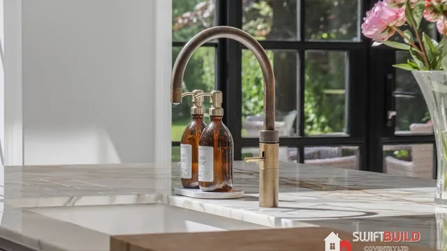 Bronze tap and marble-effect worktop in a refurbished kitchen